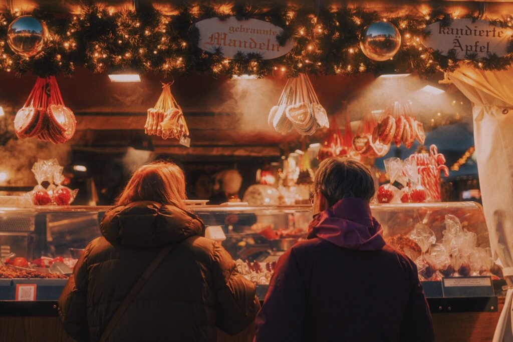 Menschen stehen vor einer festlich geschmückten Weihnachtsbude.